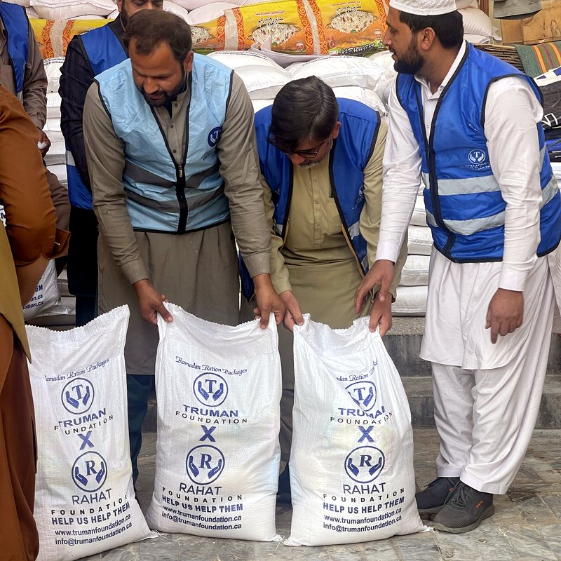 Volunteers holding Truman Foundation × Rahat Foundation branded ration sacks