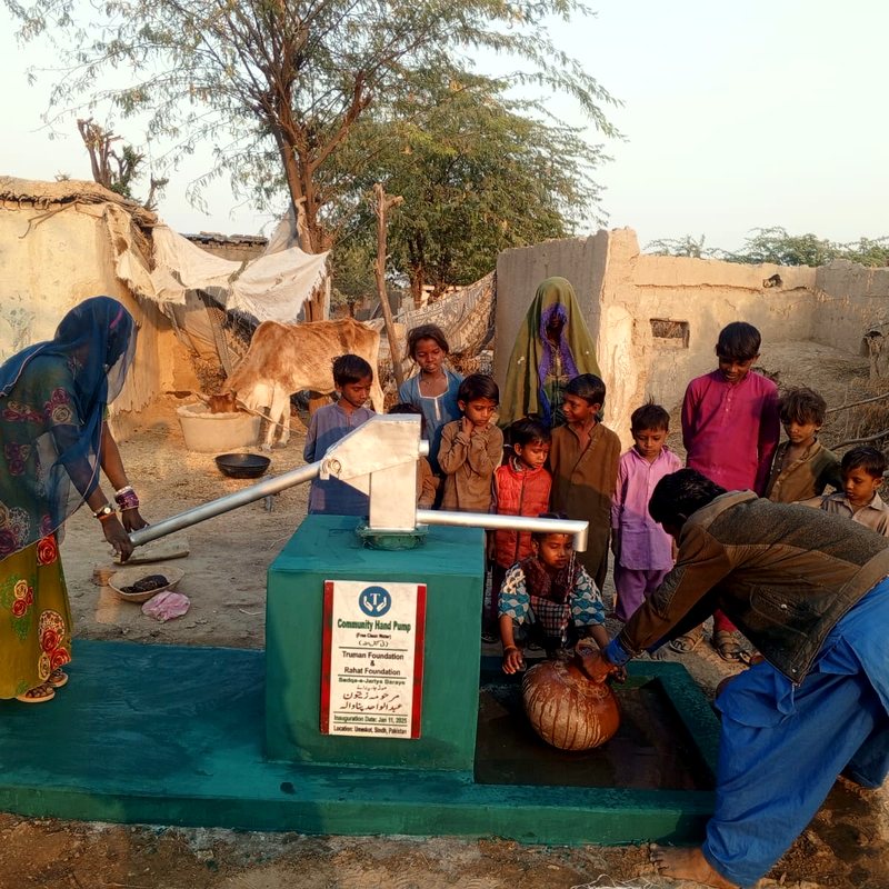 Villagers gathered around a newly inaugurated community hand pump at golden hour